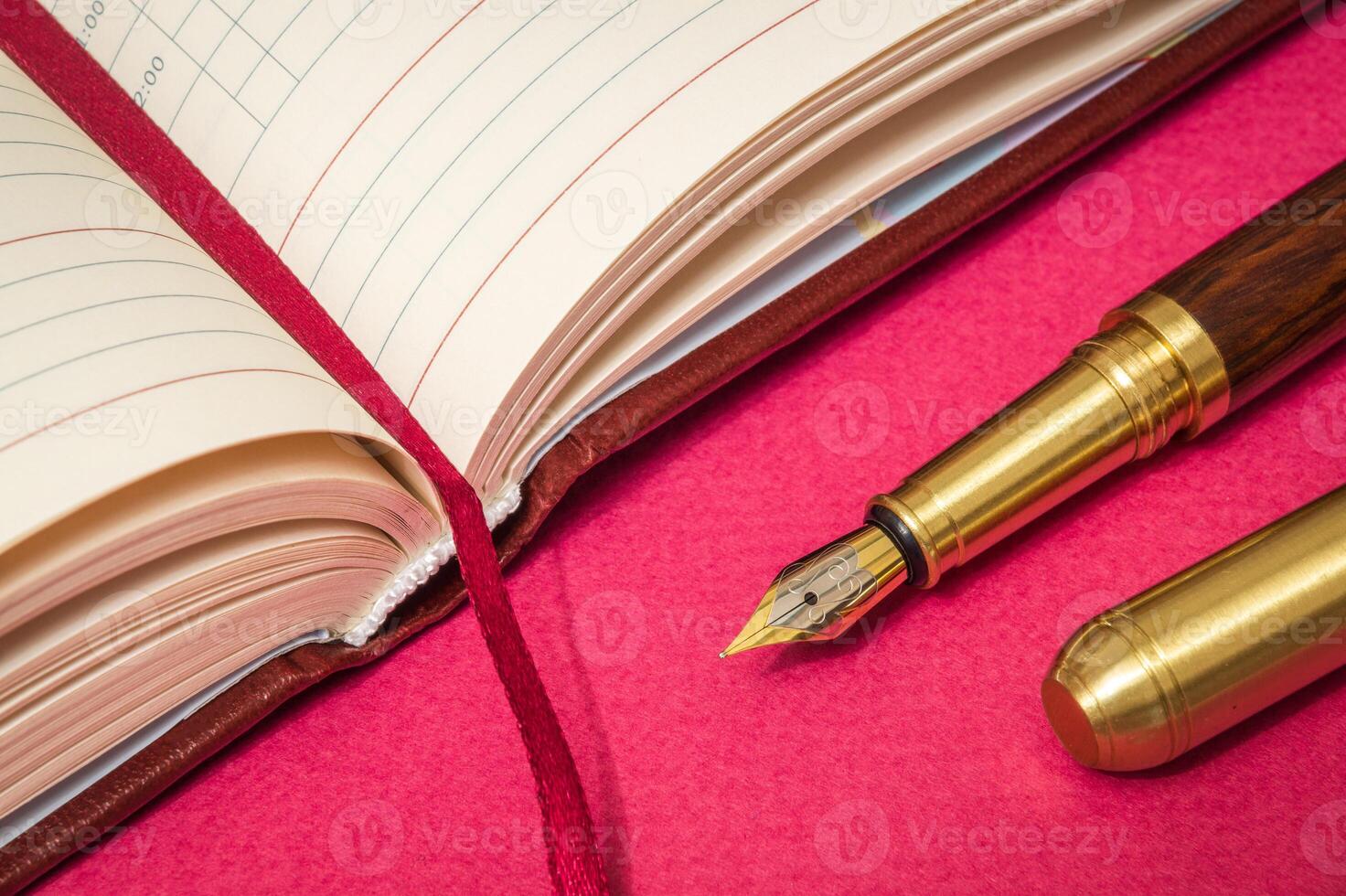 Office still life on red table with gilded pen and a notepad is preparing for the notes photo