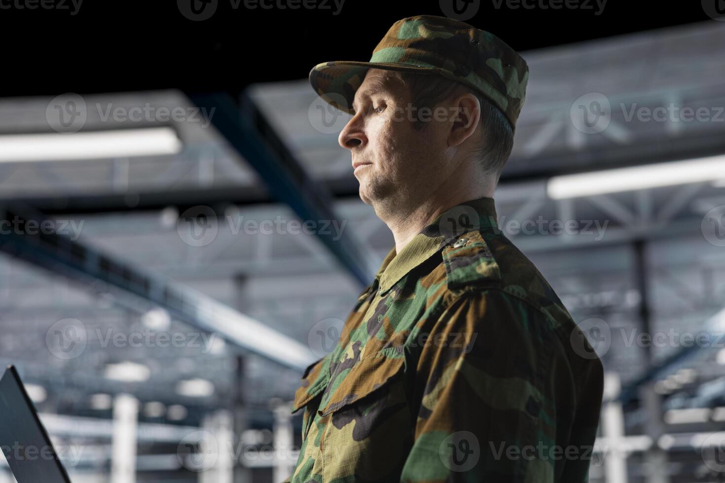 Army information technology expert in data center troubleshooting military computer systems and networks using laptop. Soldier in command center server room using notebook device photo