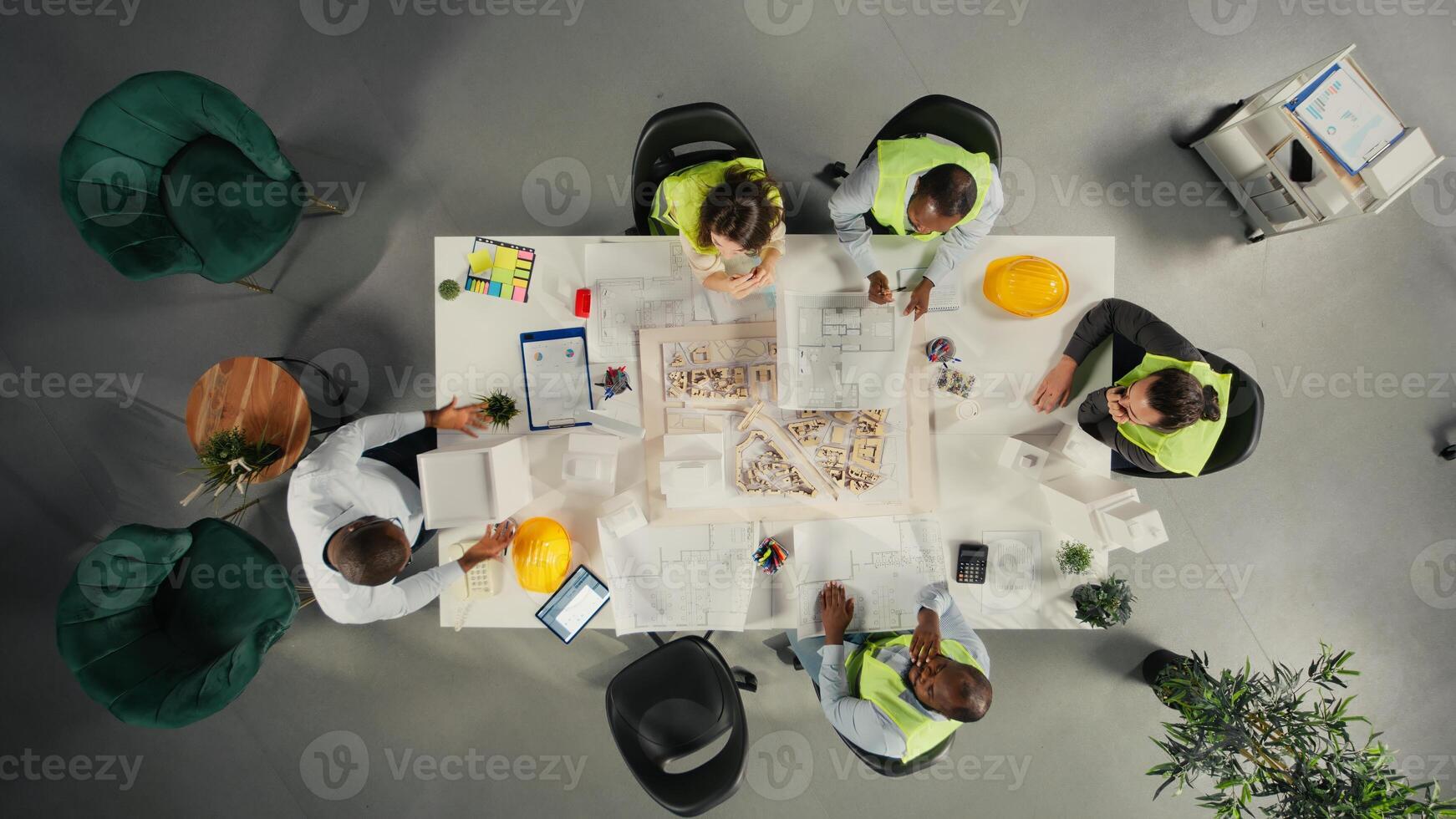 Top down view of property developers and architects in meeting reviewing blueprints and structural designs. Team discusses project approval and city planning for housing growth. photo