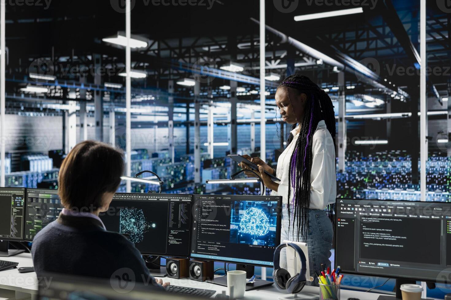 System administrators in data center troubleshoot server connectivity issues using AI. African american woman and technician in server room auditing systems for vulnerabilities photo