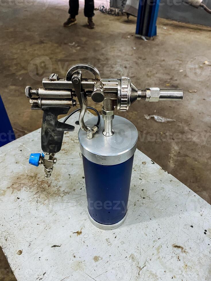 workshop bench with lubrication tool, chrome nozzle pressure trigger for lubrication, mobilized lubricant spray device featuring pressure trigger and chrome nozzle for detailed lubrication photo
