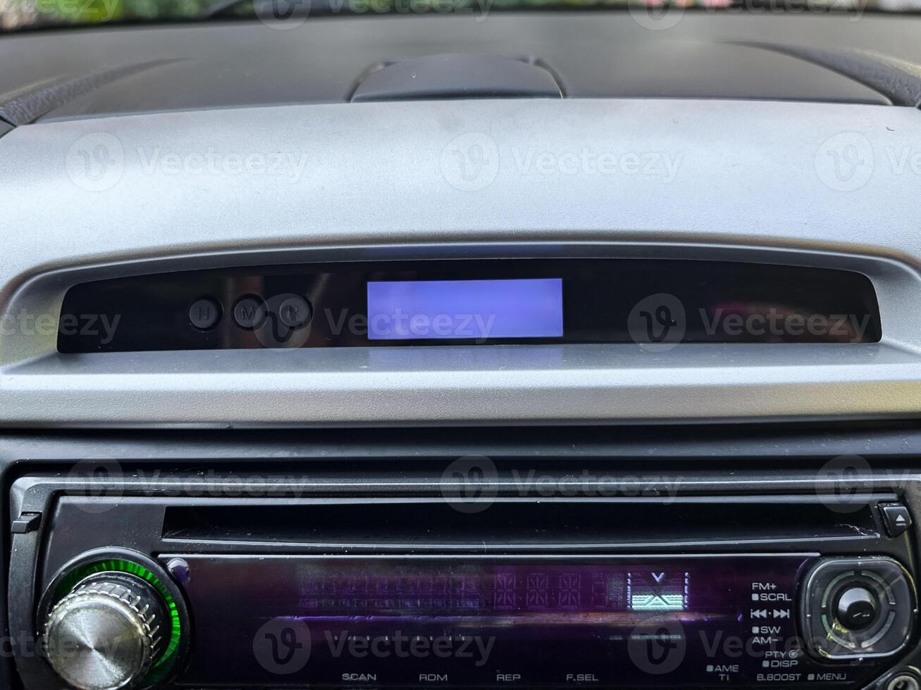 Dashboard of a car showing a blank screen and audio controls while parked in a quiet neighborhood on a sunny afternoon photo