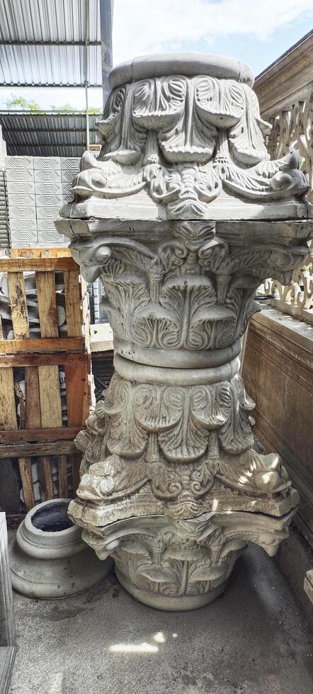 A ornate architectural column capital with elaborate carved floral and leaf patterns. The design appears to be inspired by classical or Corinthian style stone craftsmanship, emphasizing symmetry. photo
