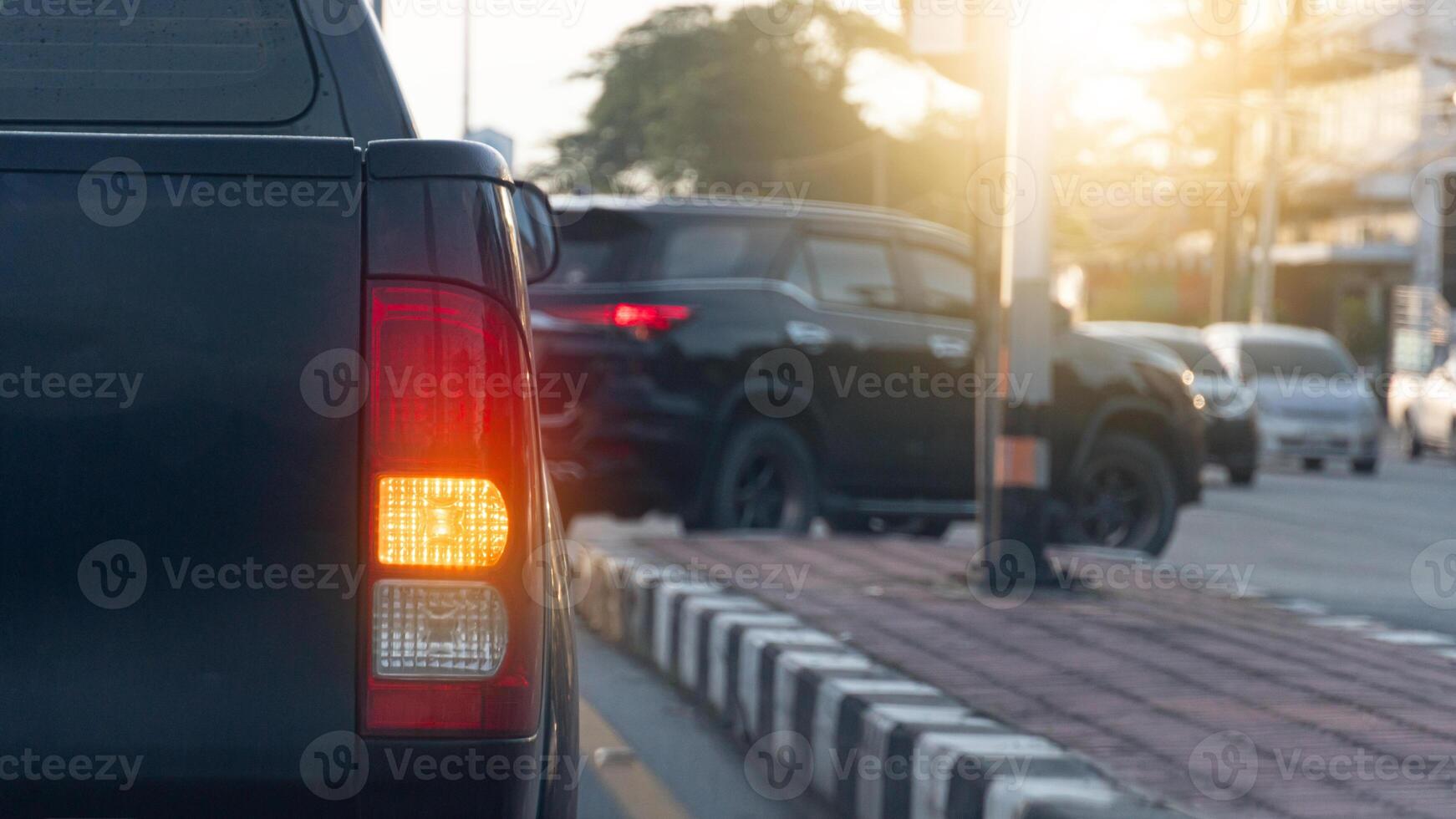 Rear side of pickup car black color with turn on signal right. Park to wait for a U-turn. Car in front is about to make a U-turn. Blurred of many cars are driving by. photo