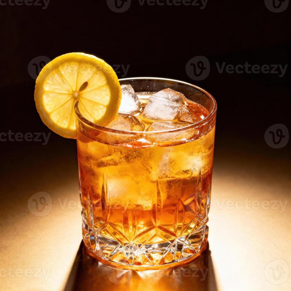 Amber colored beverage with ice and citrus garnish rests on illuminated surface photo