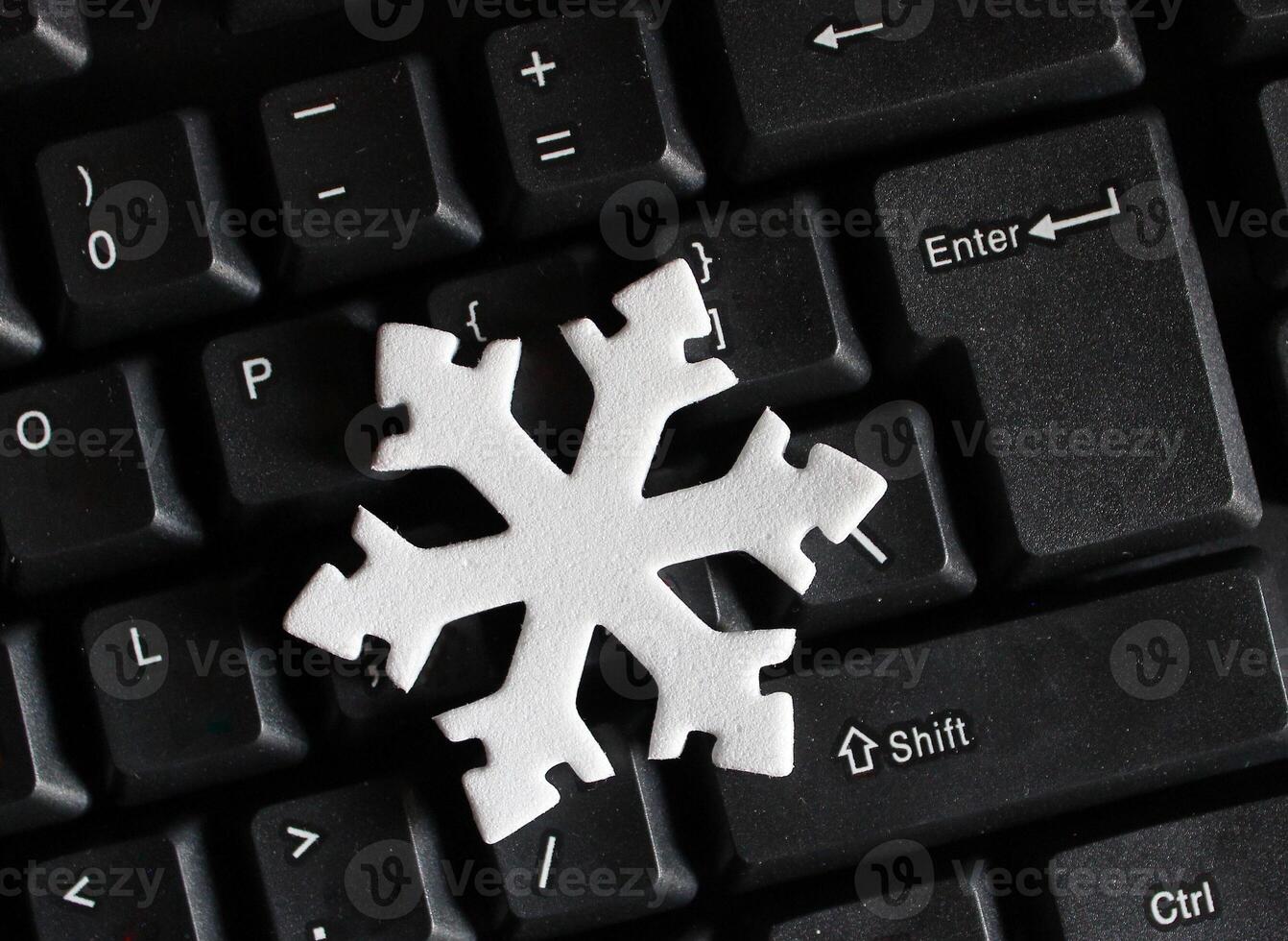 Artificial Snow Sign Near Enter Button on Black Keypad. White Snowflake on a Black Keyboard photo