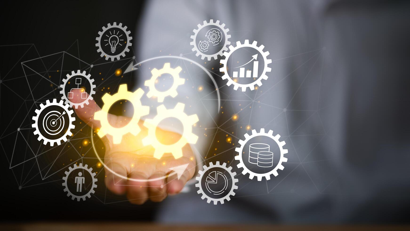 A businessman holding virtual gear icons in hand, symbolizing business process automation, system integration, workflow management, and efficiency improvement through innovative digital technology. photo