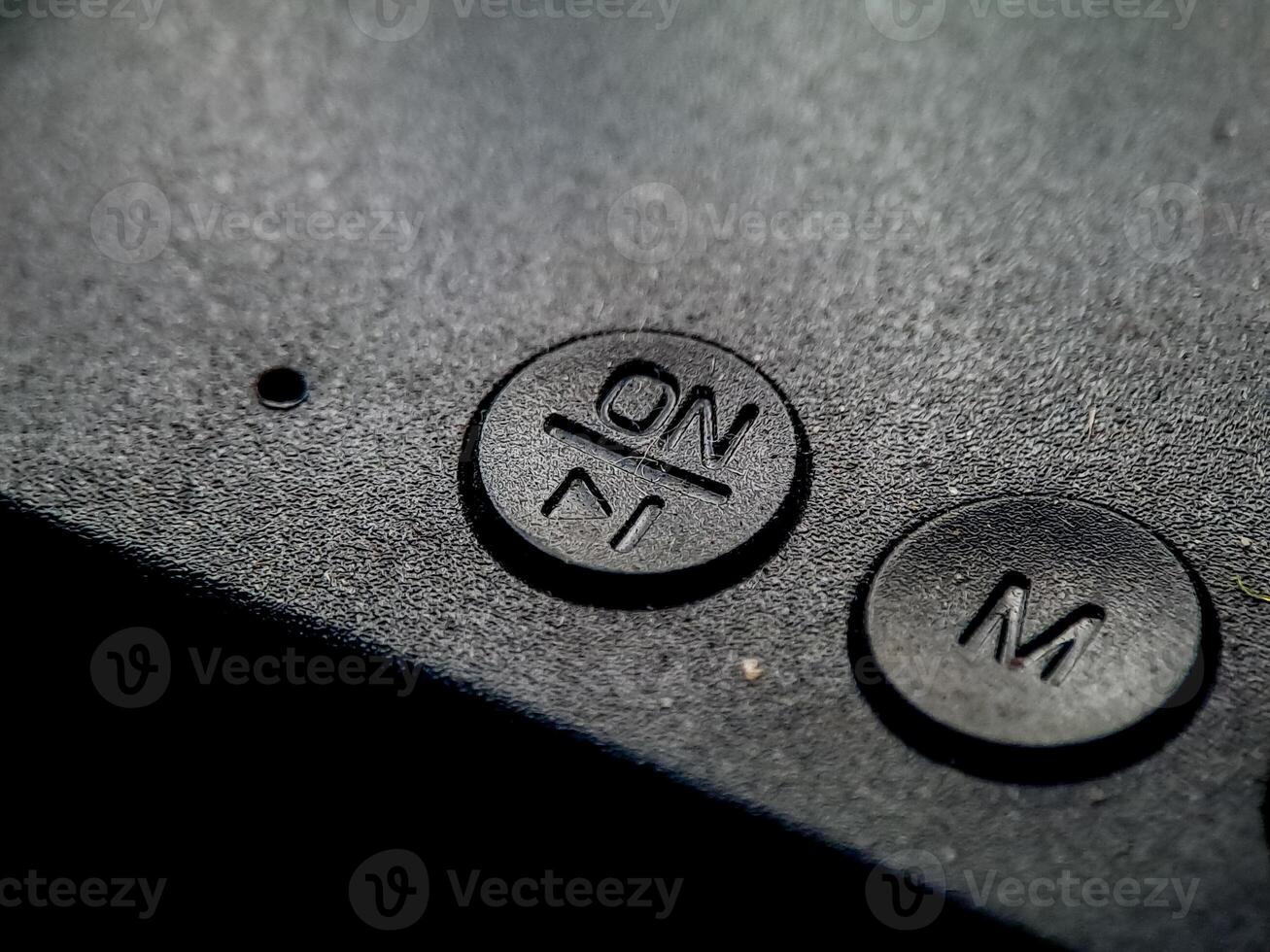 Textured surface showing raised 'On' and 'M' buttons, implying power and mode control setting photo