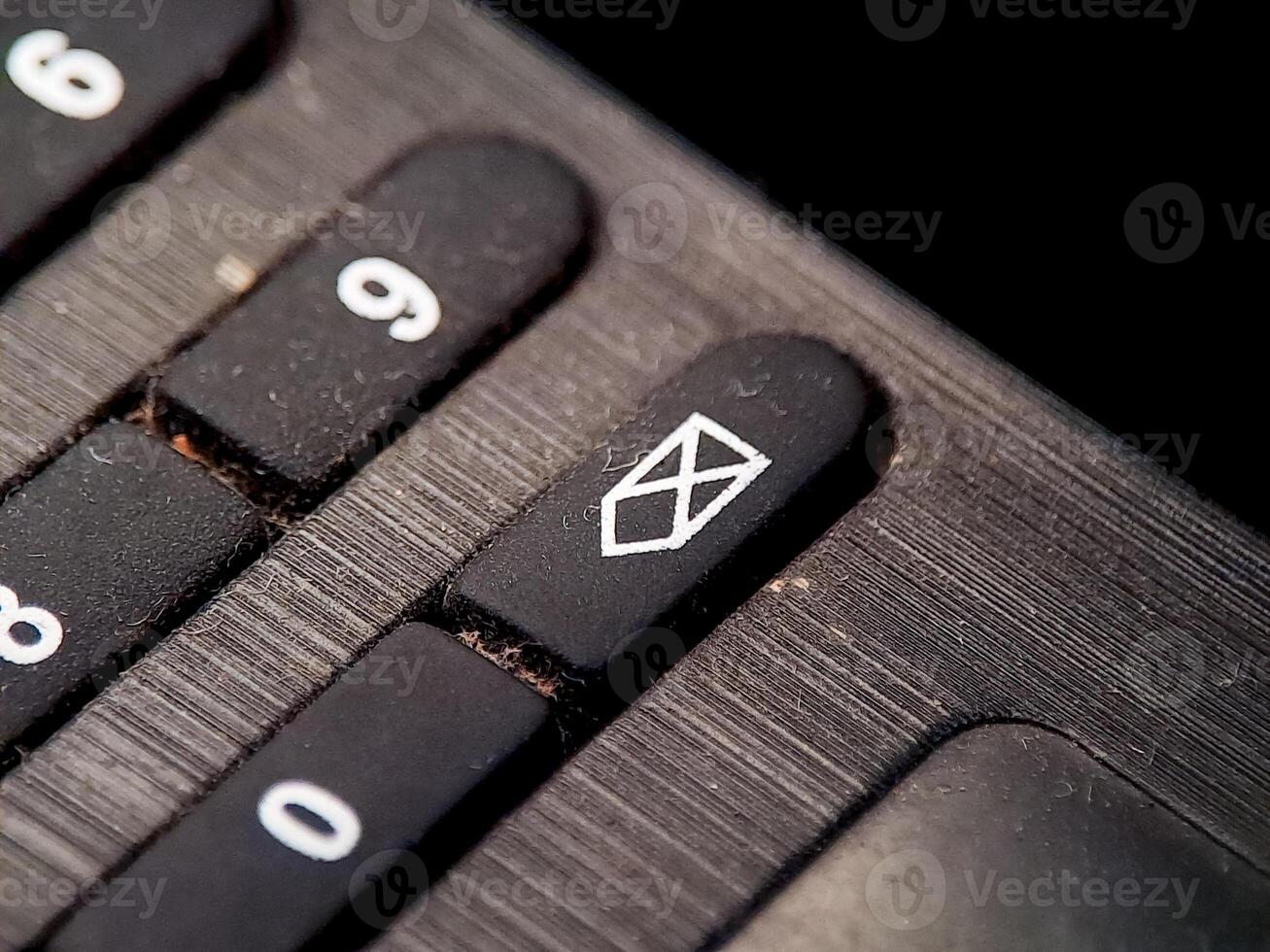 Macro image highlighting a mute function key on a dark, textured electronic device panel. photo