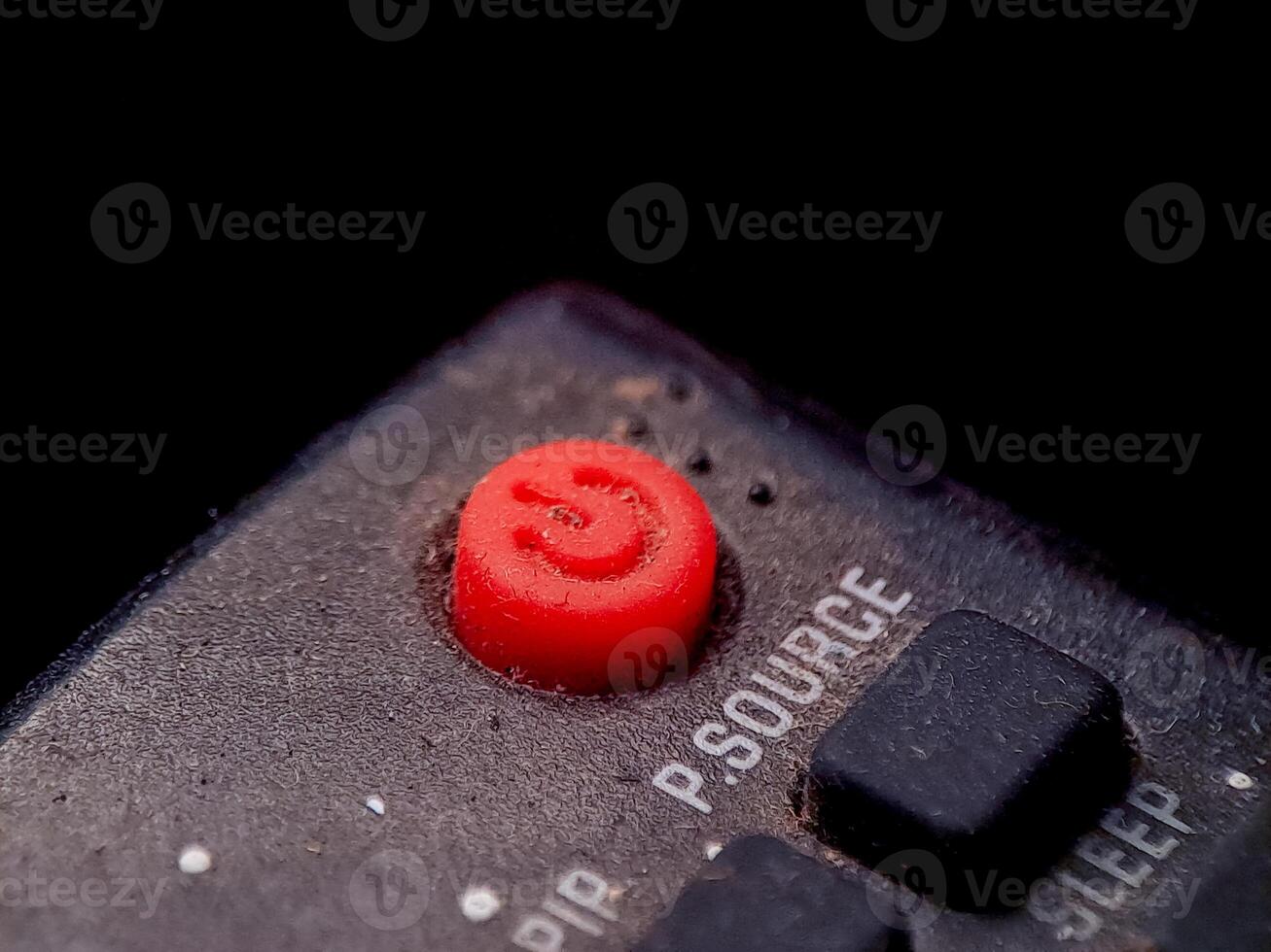 Close up image showing a red power button on a remote with a rough textured surface. photo