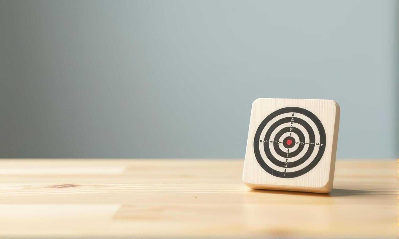 Wooden block with target design featuring concentric circles and red center is placed on light wooden surface against plain background. image conveys focus and precision photo