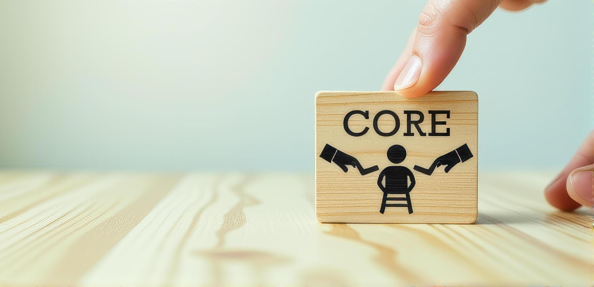 Wooden block with word CORE and symbol of person being targeted by arrows is held by hand on wooden surface, symbolizing focus and pressure photo