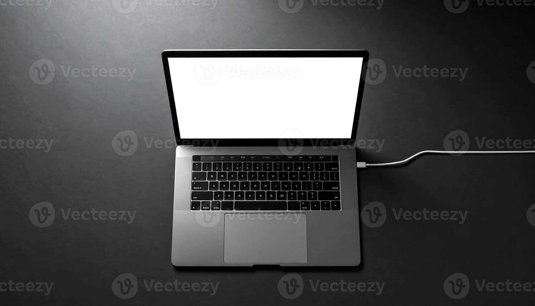 Modern laptop with blank white screen on dark surface, connected to power source, with sleek and minimalist design, suitable for work or entertainment, emphasizing technology and connectivity photo