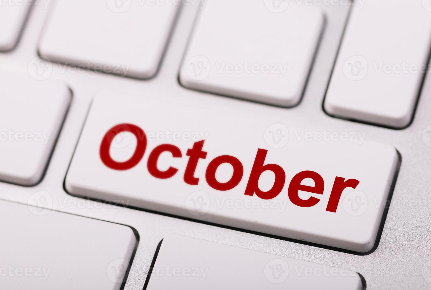 Close-up of a keyboard with a white key labeled October in bold red letters, representing digital time management or monthly scheduling. photo