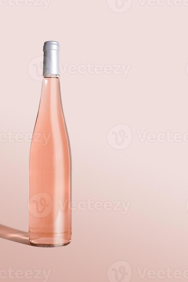 Rose wine bottle on table on gradient pink background, side view. Mock up product alcoholic drink in sunlight. One bottle Rose wine template, minimal style still life, monochrome pastel color. photo