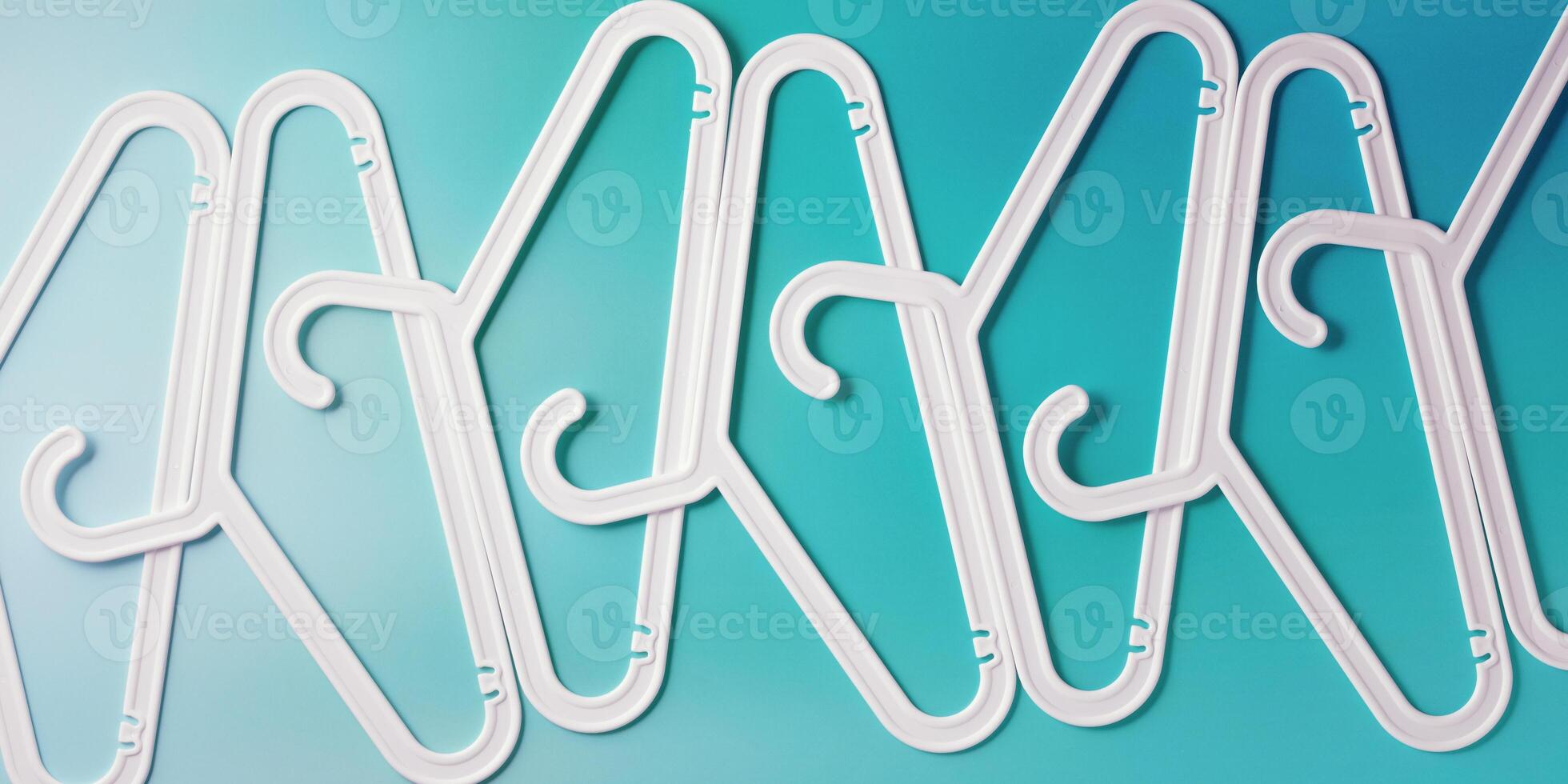 White Clothes hangers as creative minimal composition on teal gradient background, Plastic racks creating modern and geometric aesthetic, top view banner, creative photo, smooth lines pattern photo