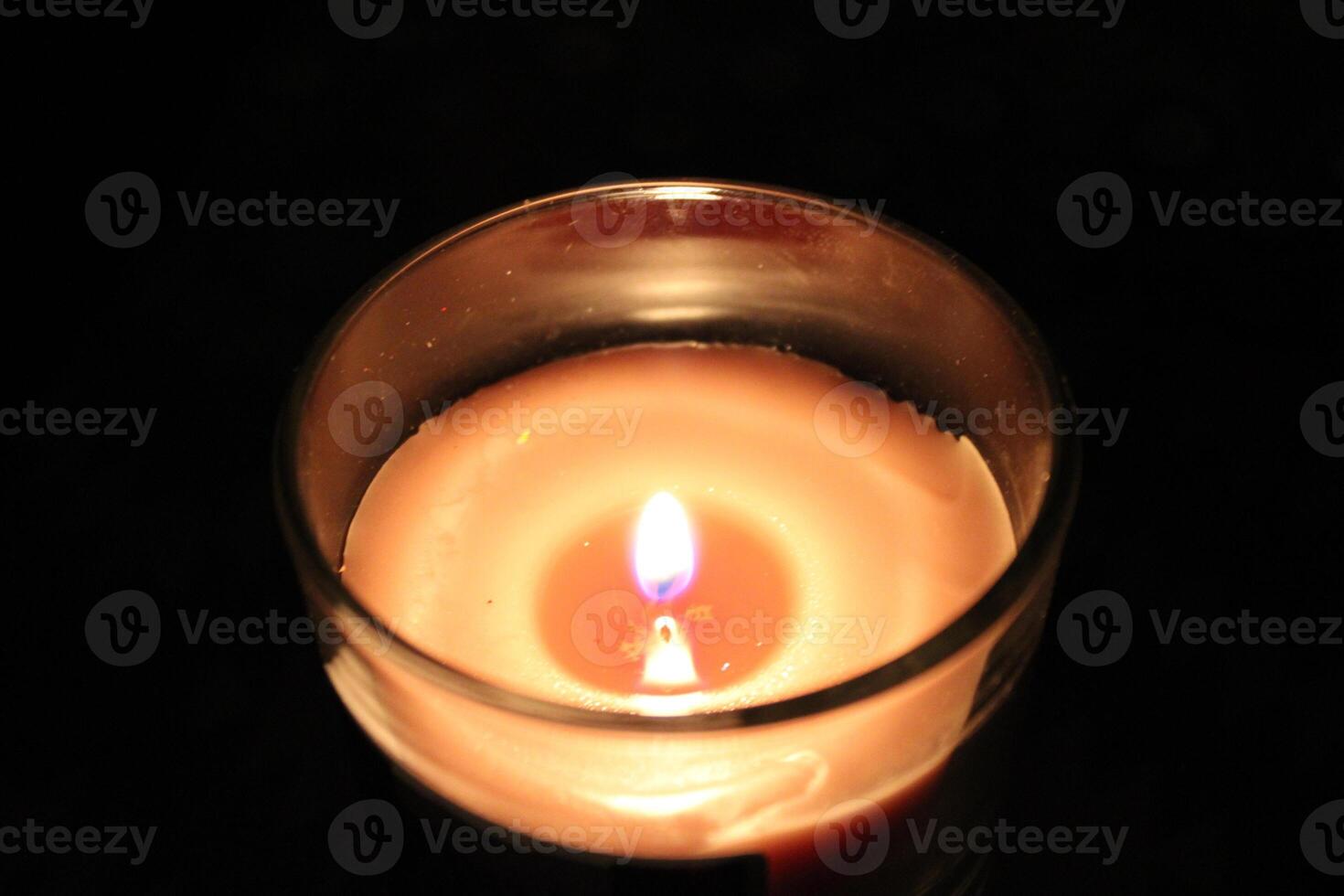 Candle flame flickers gently in a dark room creating a warm and calming atmosphere during a quiet evening photo