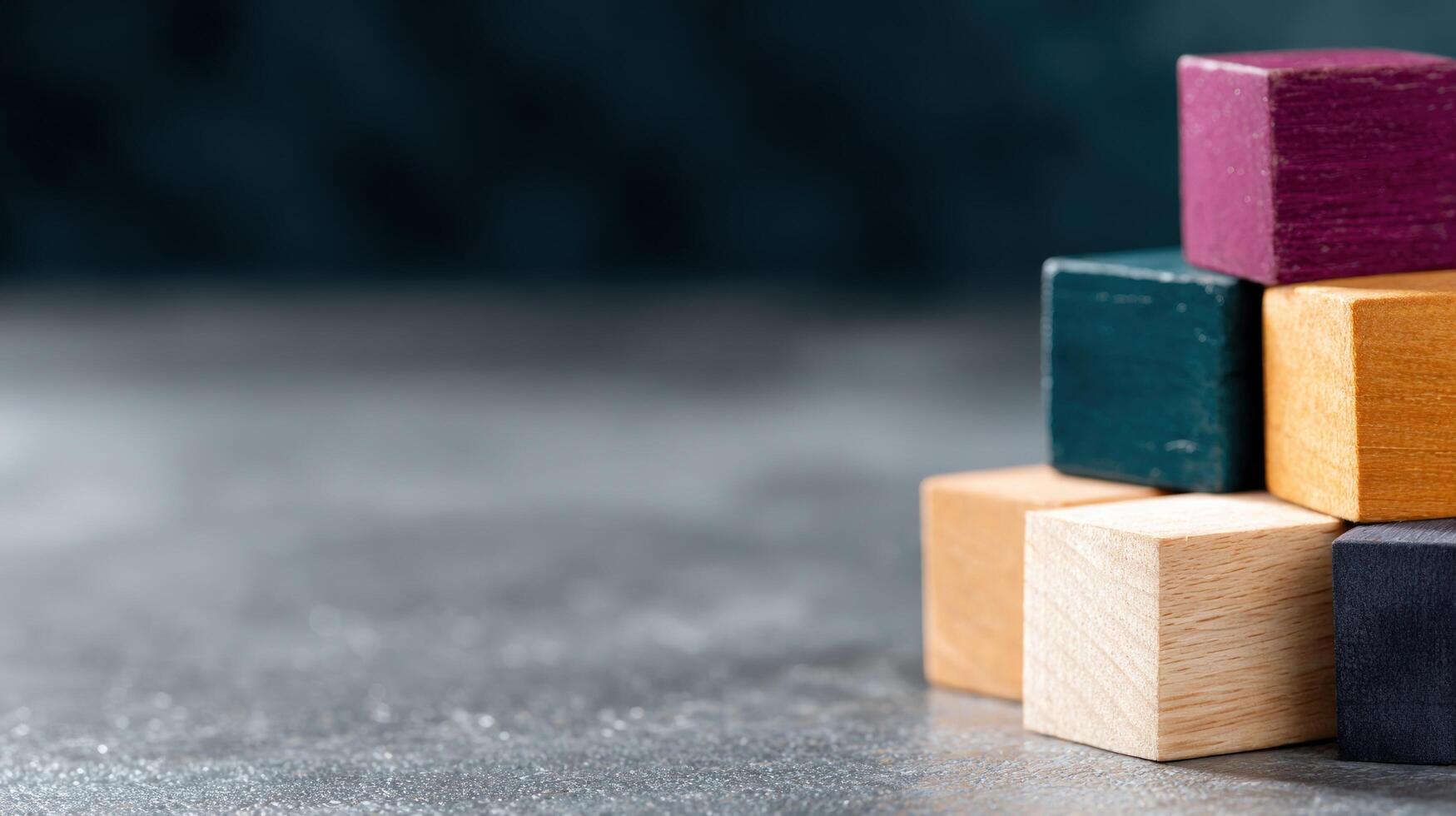 Multicolored wooden building blocks stacked on dark textured background displaying progress and development concept photo
