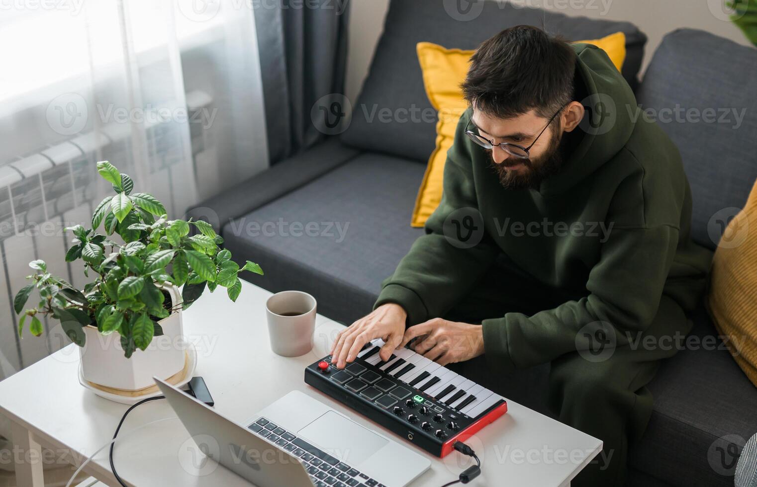 Top view Man music producer or arranger using laptop and midi keyboard and other audio equipment to create music at home studio. Beat making and arranging audio content and composing song photo