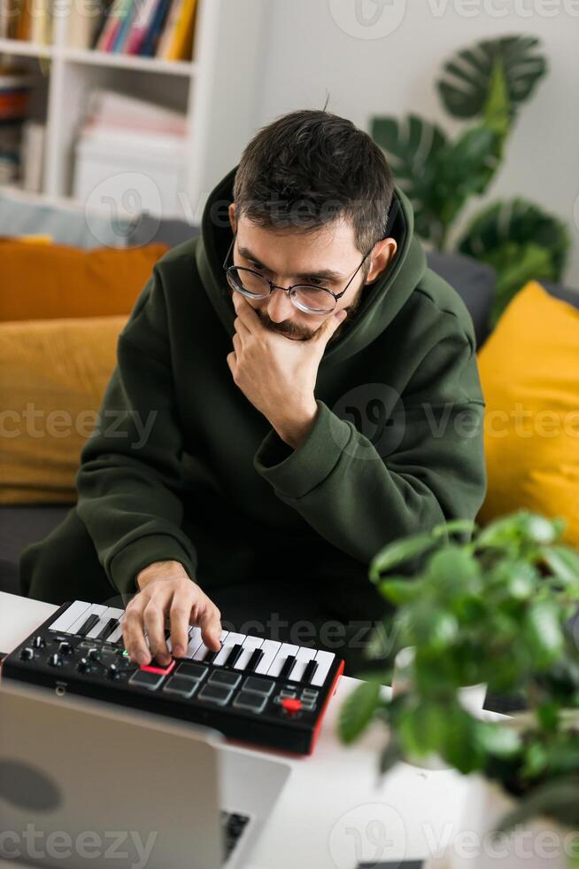 Man music producer or arranger using laptop and midi keyboard and other audio equipment to create music at home studio close-up. Beat making and arranging audio content and composing song concept photo