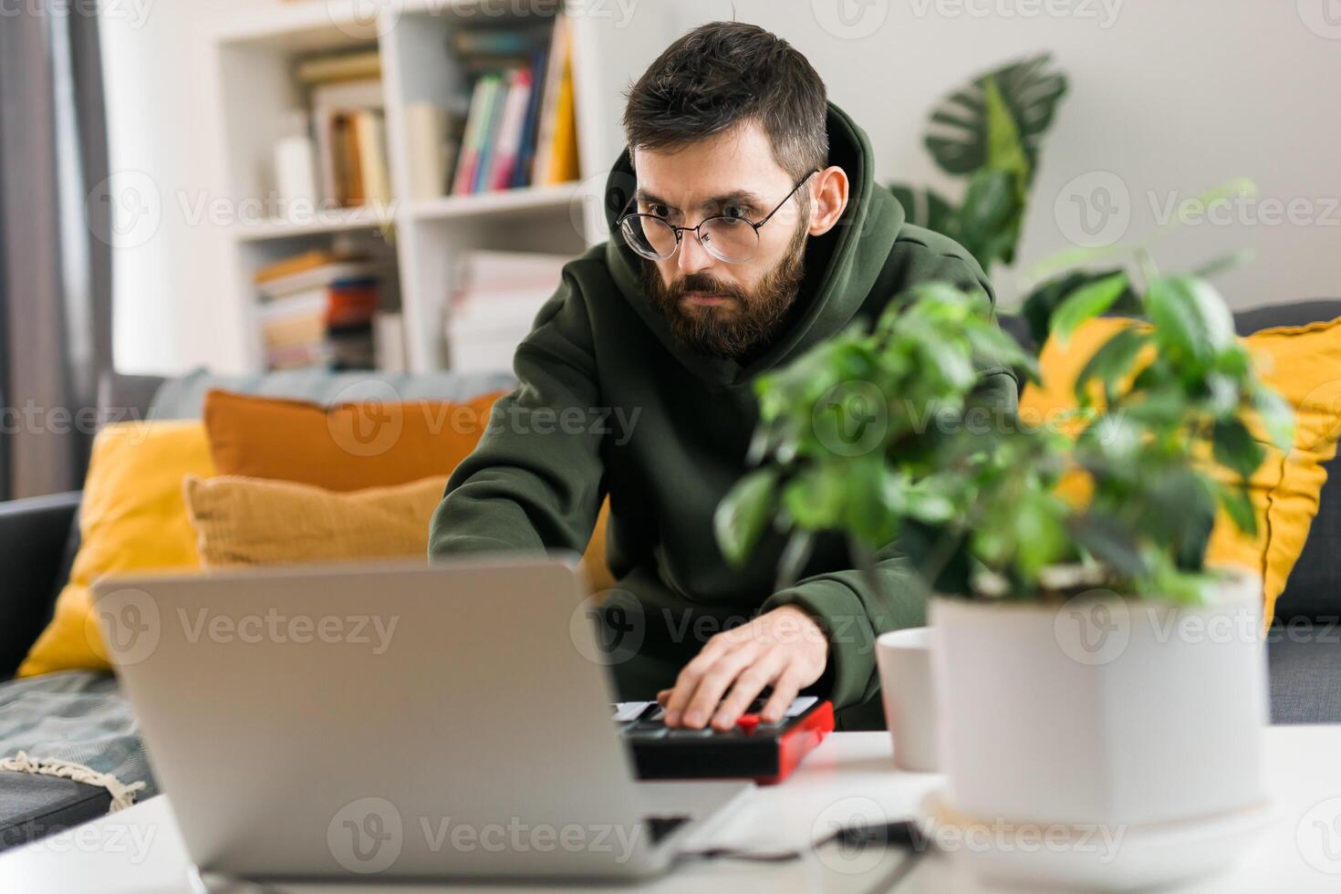 Portrait Man music producer or arranger using laptop and midi keyboard and other audio equipment to create music at home studio. Beat making and arranging audio content and composing song concept photo