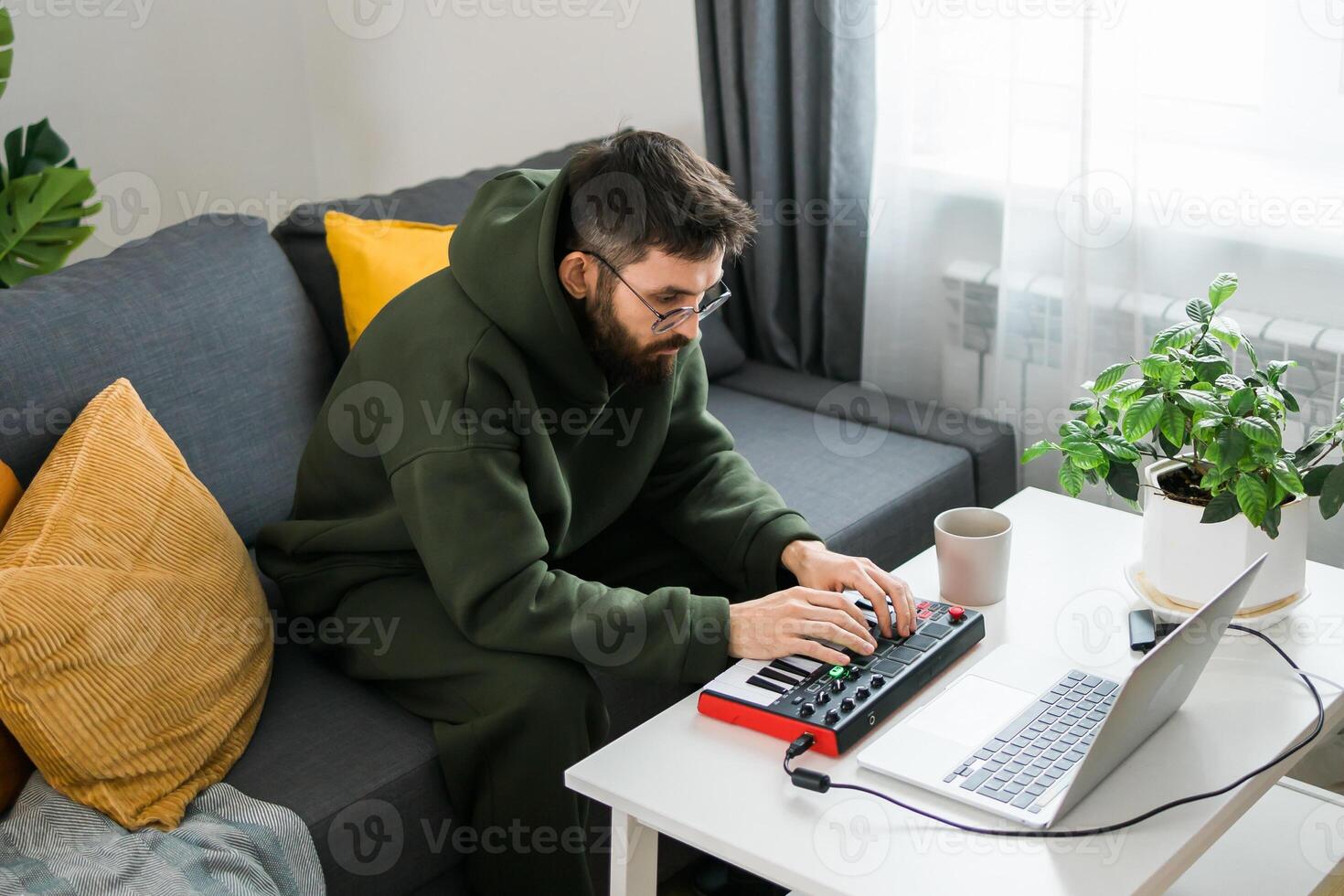 Male music producer or arranger using laptop and midi keyboard and other audio equipment to create music at home studio. Beat making and arranging audio content and composing song. photo