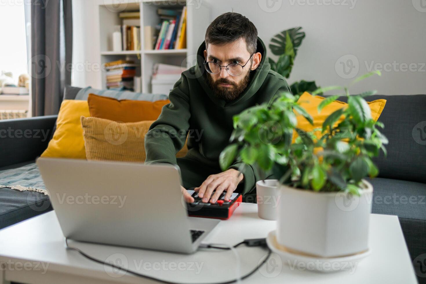 Close-up Man music producer or arranger using laptop and midi keyboard and other audio equipment to create music at home studio. Beat making and arranging audio content and composing song concept photo