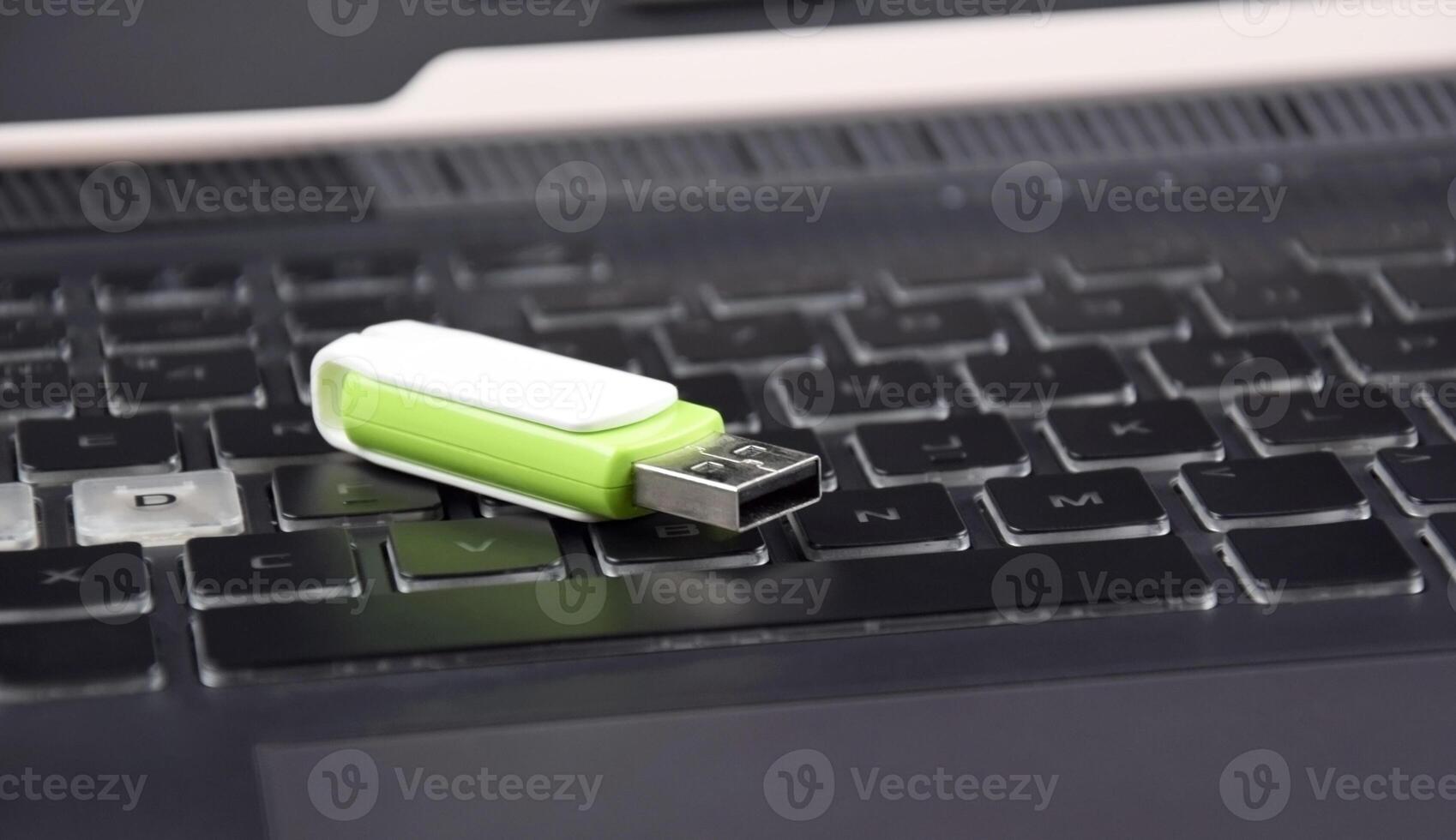 One USB memory stick or flash drive on the keyboard of an open laptop. photo