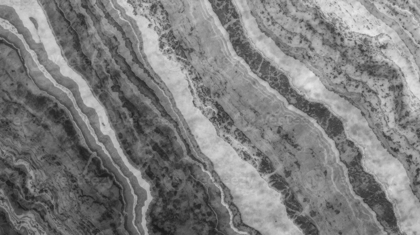 The monochromatic stone texture displays wavy patterns and mineral deposits creating a natural and sophisticated surface appearance overall. photo