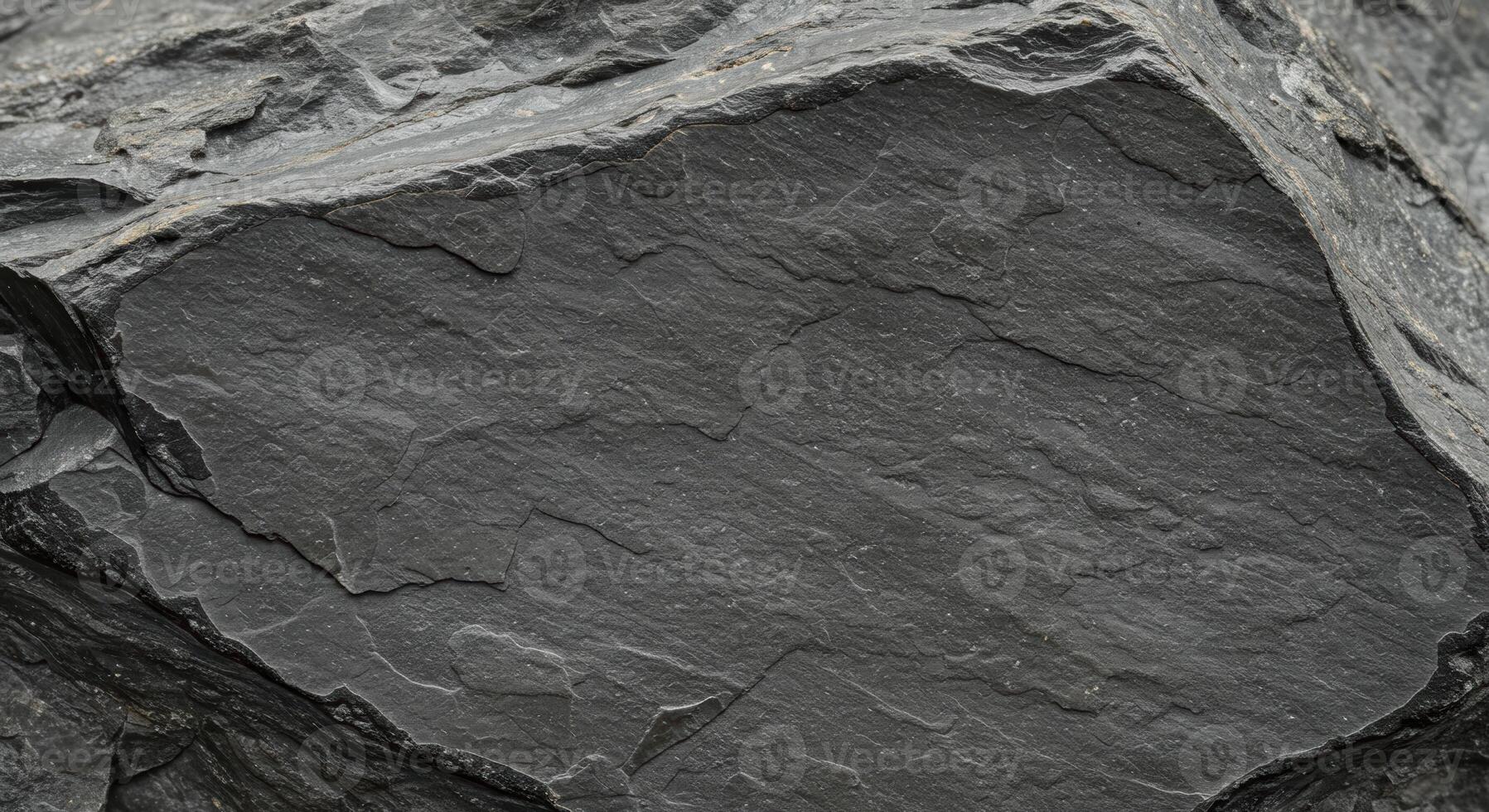 Close up detail of fractured dark gray slate rock with rough textured surface shows natural geological pattern for abstract background use. photo