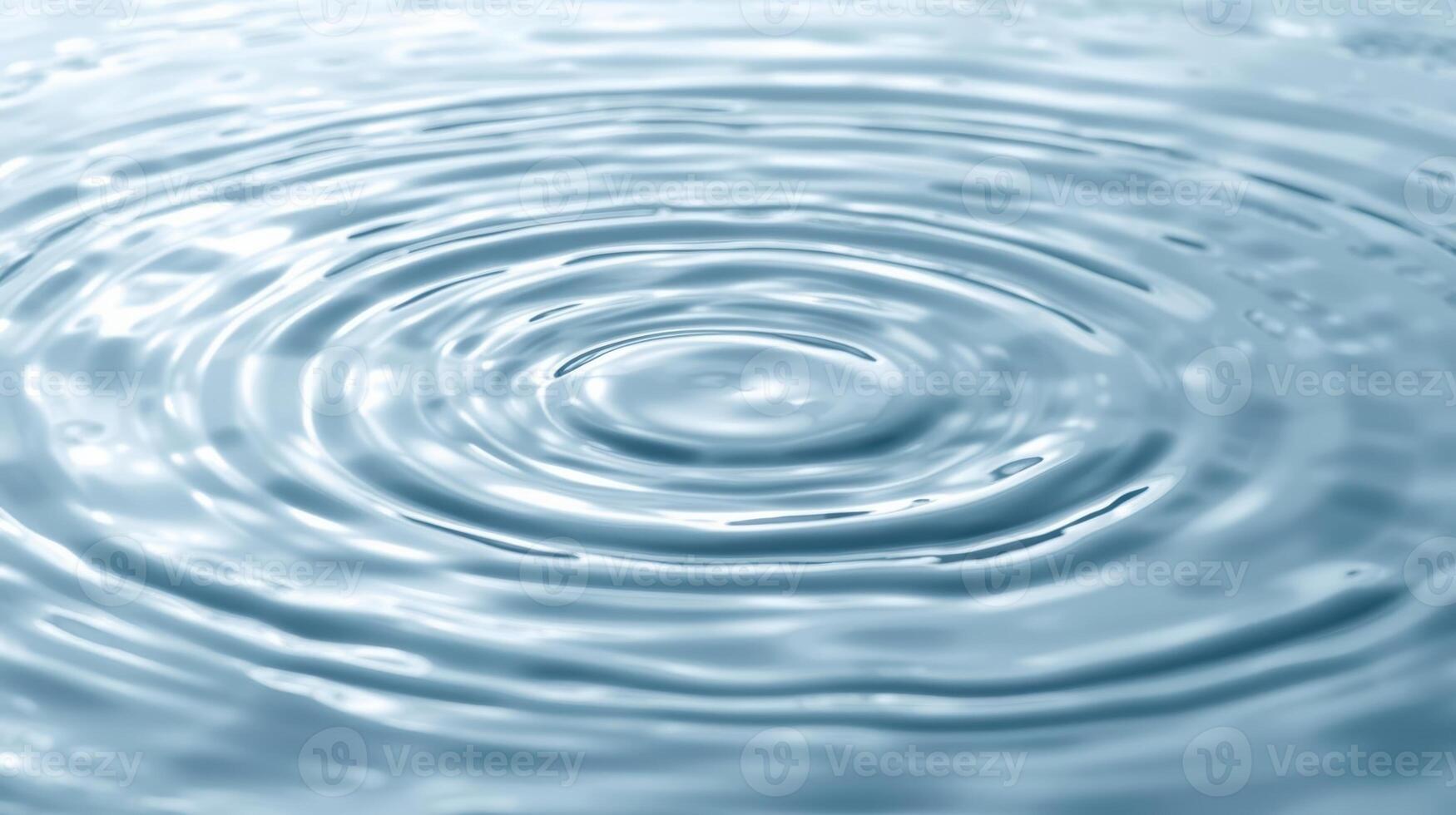 Gentle concentric circles ripple outwards from the center of a body of clear blue water creating a calming natural pattern effect. photo