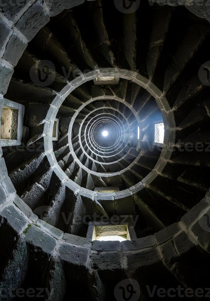 Intricate Stone Spiral Staircase with Natural Light Streaming Through Windows Creating Circular Patterns a Visual Representation of Ascent and Architectural Grandeur photo