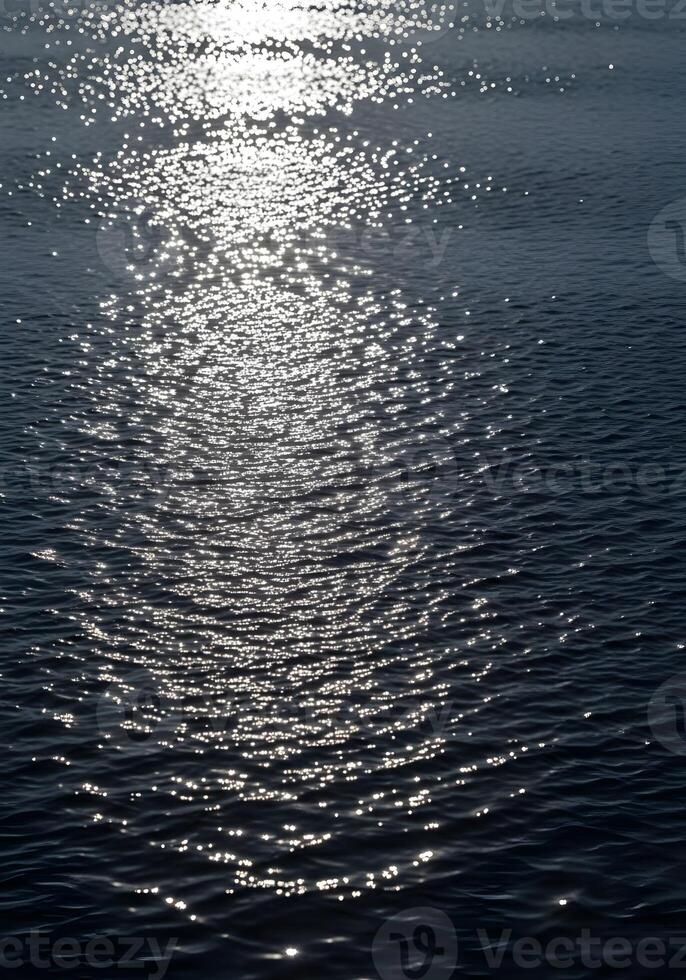 Sparkling Sunlight Dancing on Dark Ocean Waves Reflecting the Suns Rays Creating a Mesmerizing Effect on the Water Surface for Serene and Peaceful Imagery photo