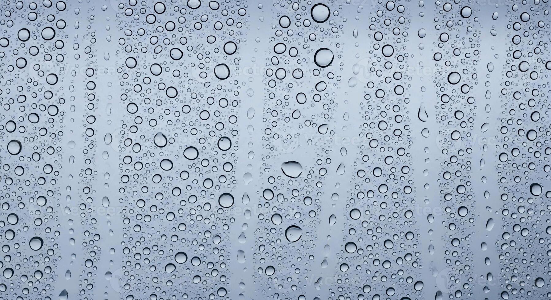 Close up view of raindrops on a window pane creating a textured abstract pattern with vertical streaks photo