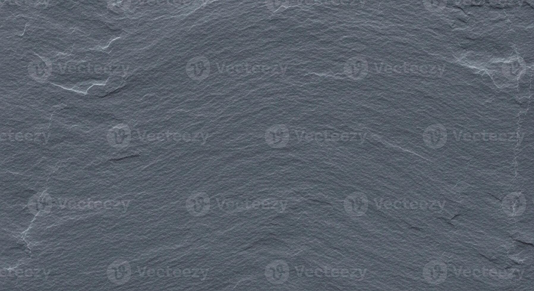 Close up textured surface of dark grey slate stone with rough irregular patterns and natural mineral variations photo