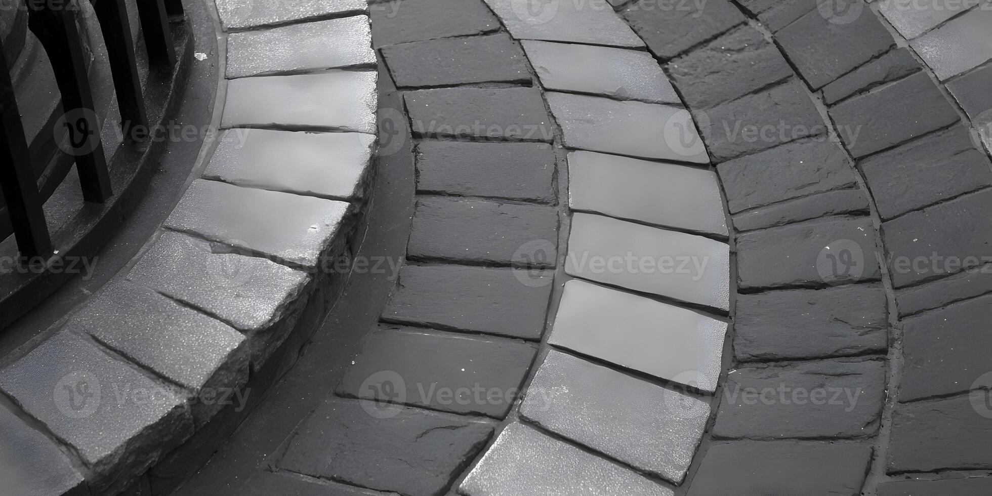 A close up view of a monochrome stone paved surface featuring light and dark grey rectangular blocks in a curving pattern photo