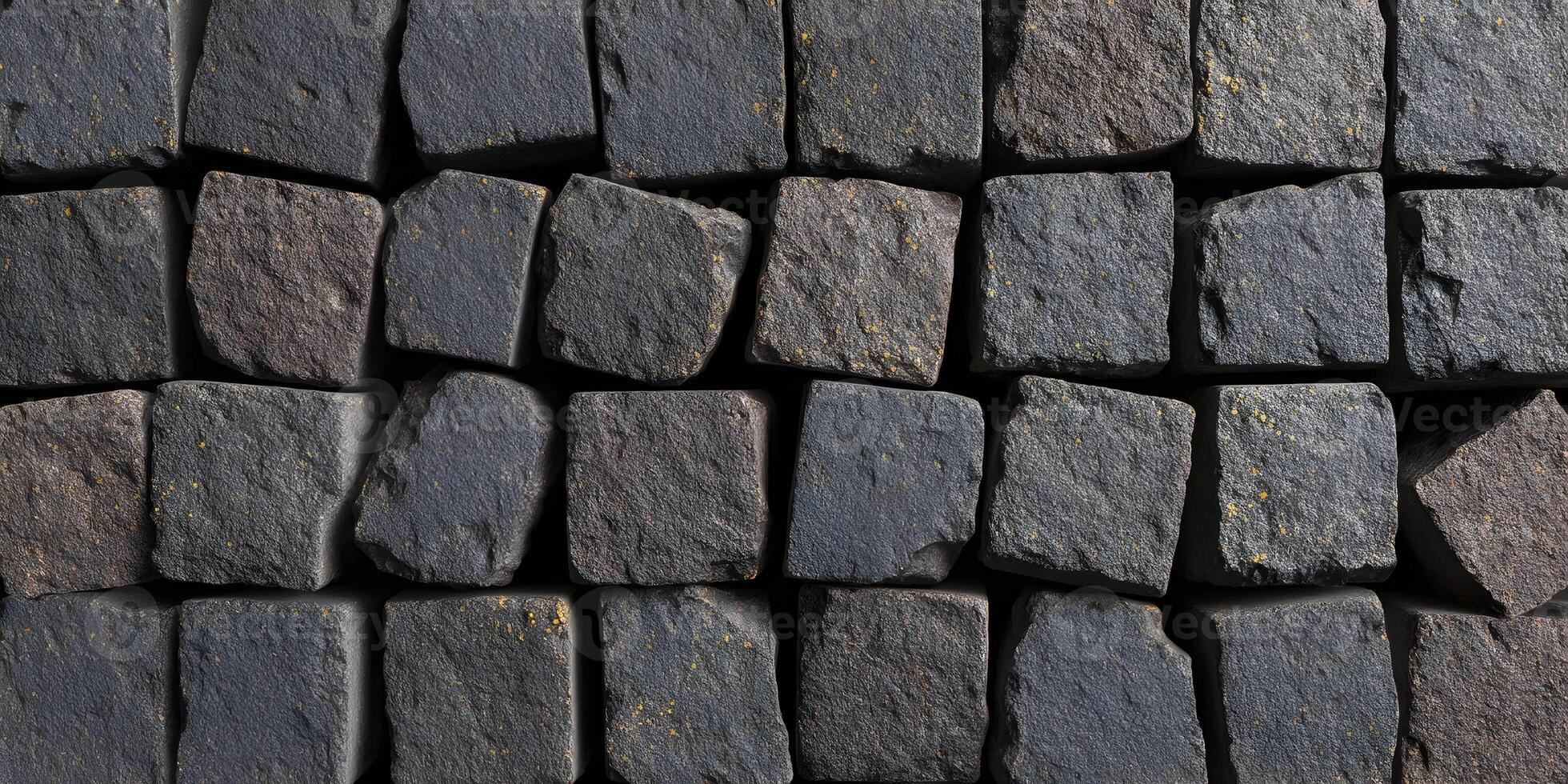 A close up view shows a rustic pattern of dark grey and brown stone paving blocks with hints of yellow photo
