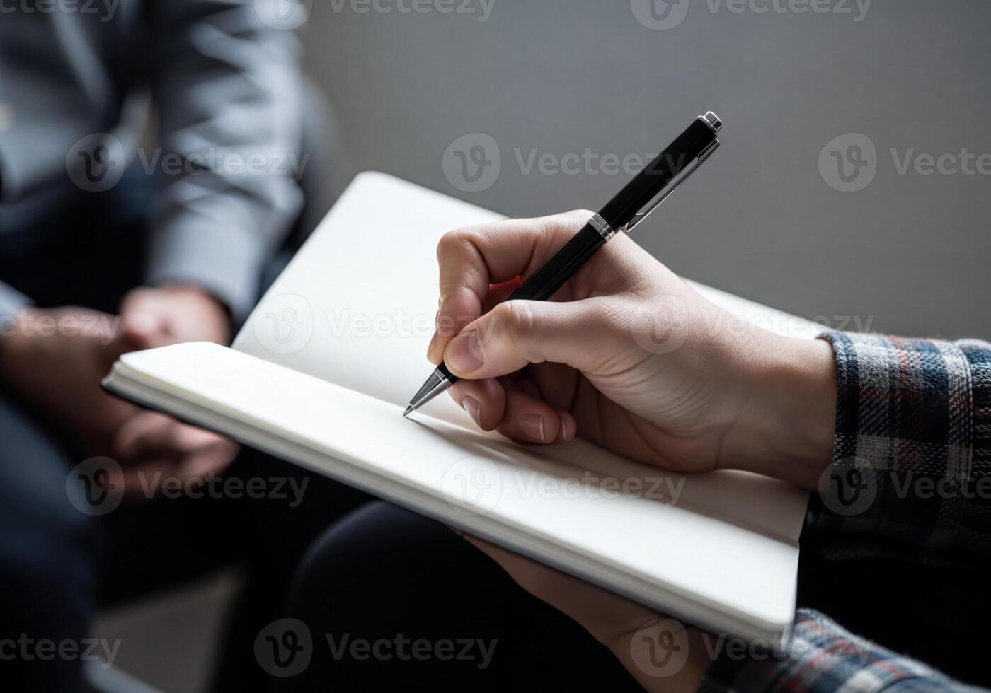 Close up of a hand writing notes with a pen in a notebook during a discussion or interview session photo
