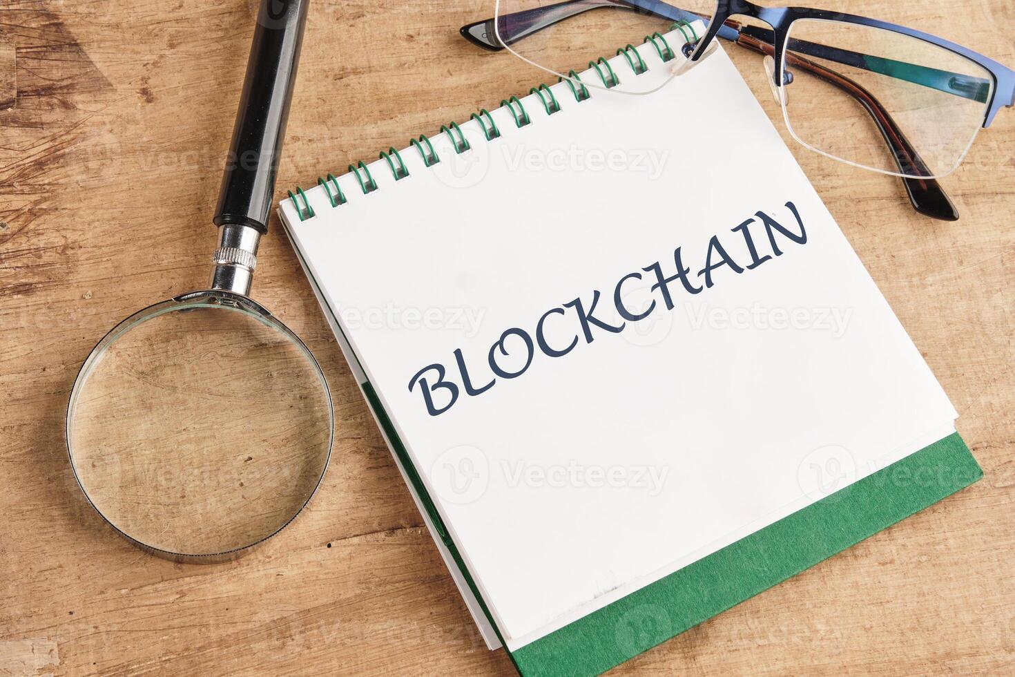 The concept of technology and development. Phrase, words, text of the BLOCKCHAIN in a notebook on an old background, in a composition with a magnifying glass and glasses photo