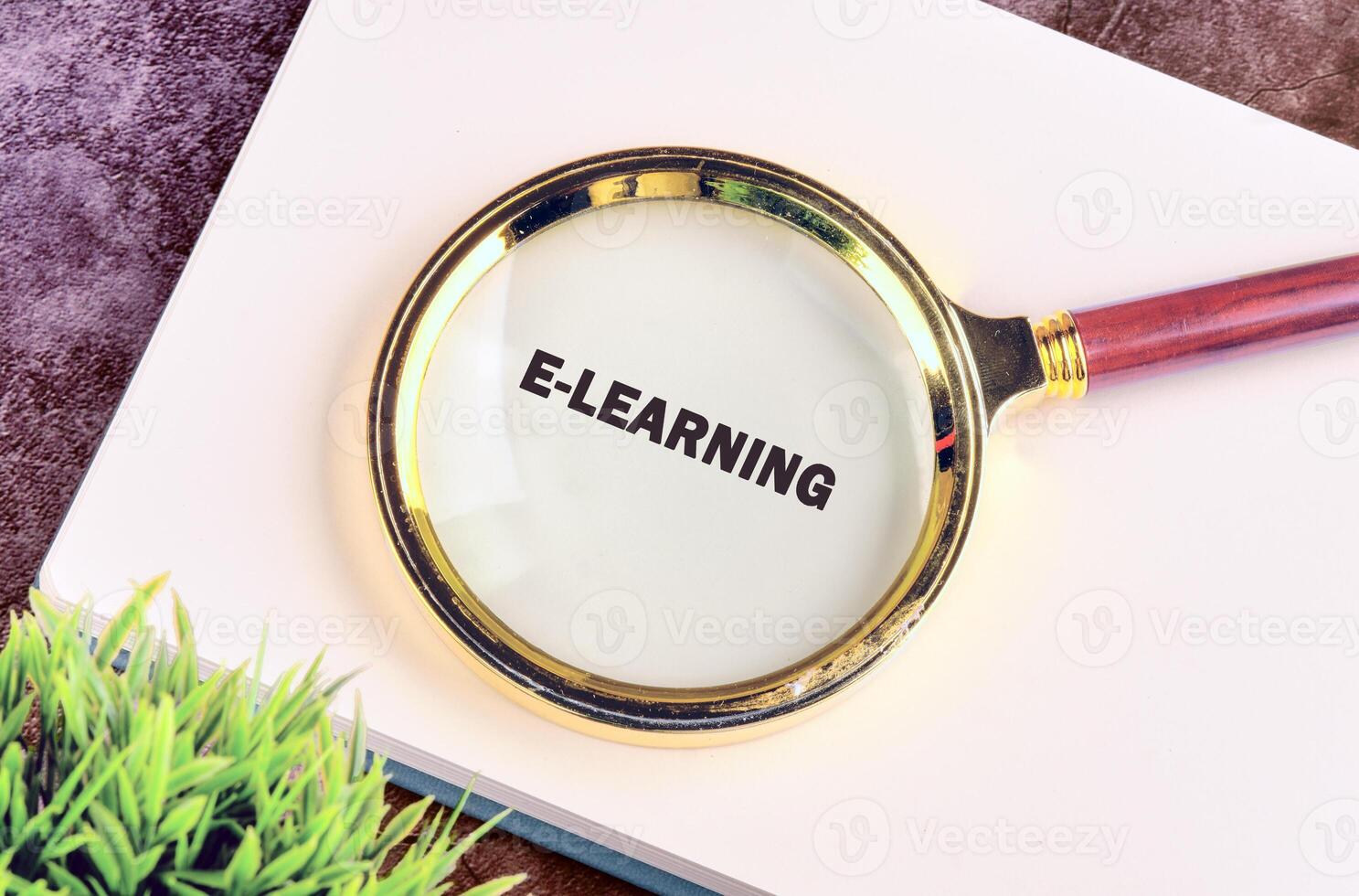 A magnifying glass is placed over the word e learning on a notebook, emphasizing the importance of online education and digital learning tools in modern times photo