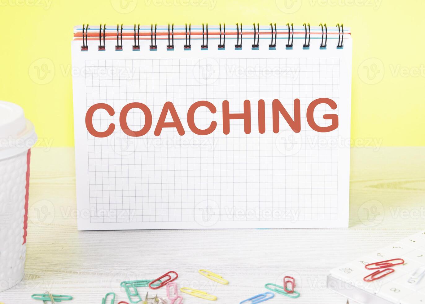 COACHING the word is written on a blank sheet in a notebook standing on a table on a yellow background photo