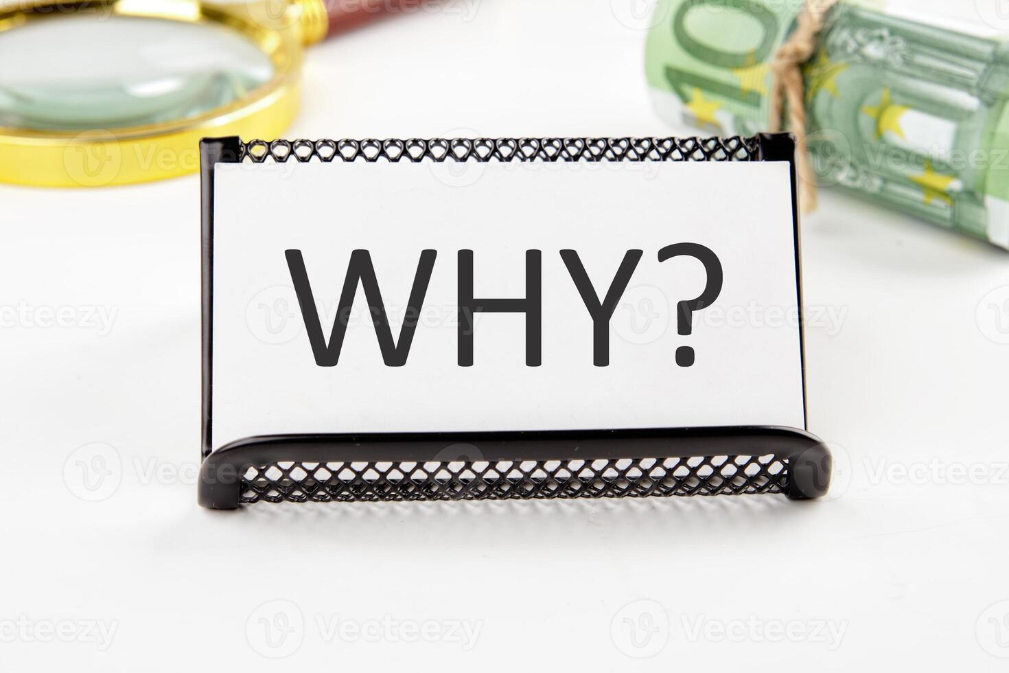WHY the text on the business card next to the roll of money with a magnifying glass in the background is out of focus on a white background photo