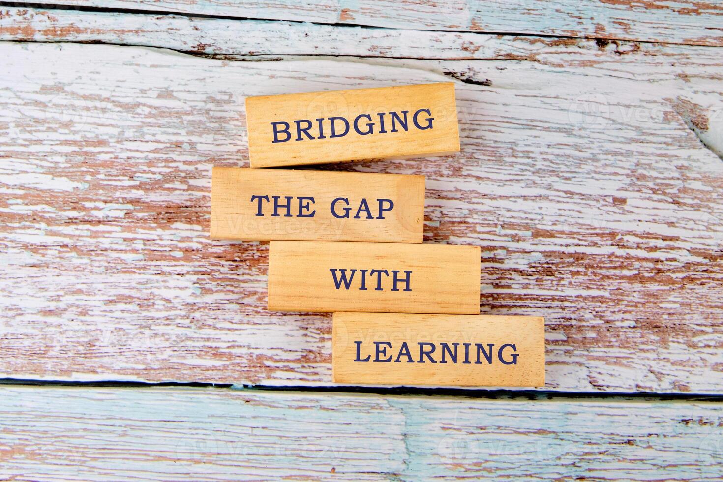 Wooden blocks display the message about bridging the gap with learning. The scene features a rustic wooden background, symbolizing the importance of education in personal development photo