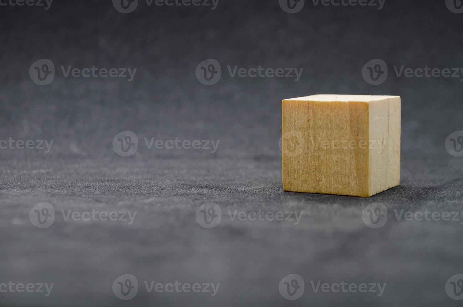 An isolated wooden cube on dark background with customizable space for text or ideas. Copy space concept photo
