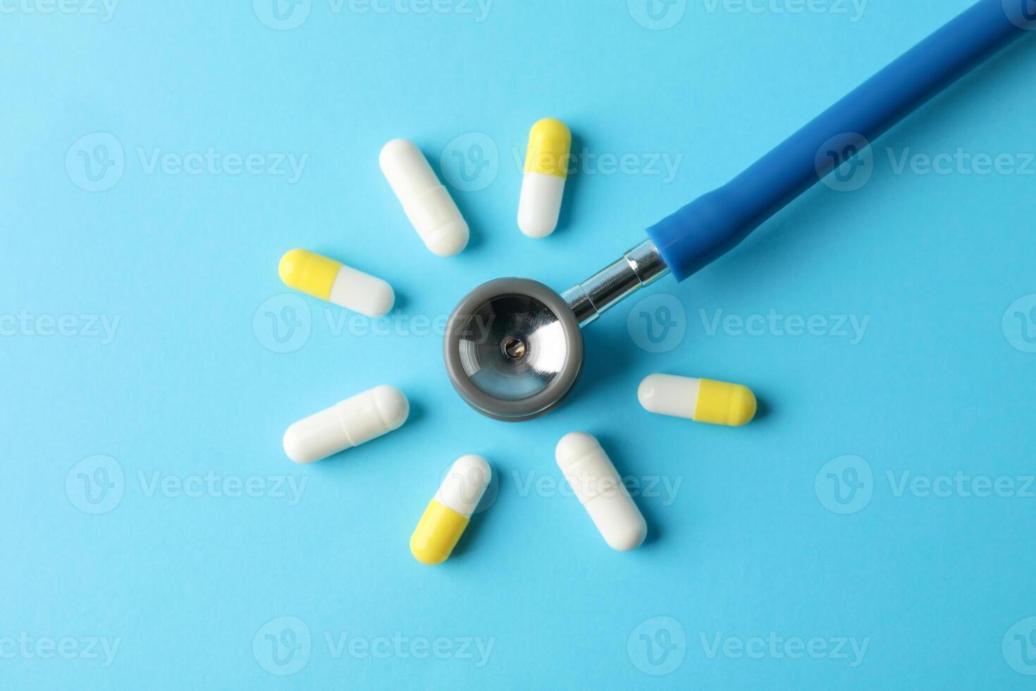 Flat lay with pills and stethoscope on blue background, top view and space for text photo