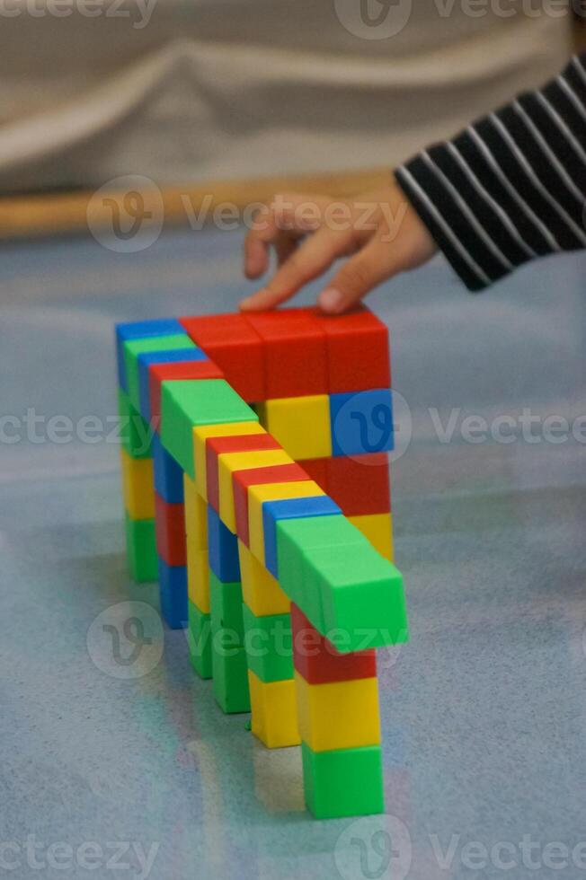 A toddler's hands building a structure using colorful blocks. This scene highlights creativity, learning, and play with colorful blocks. photo