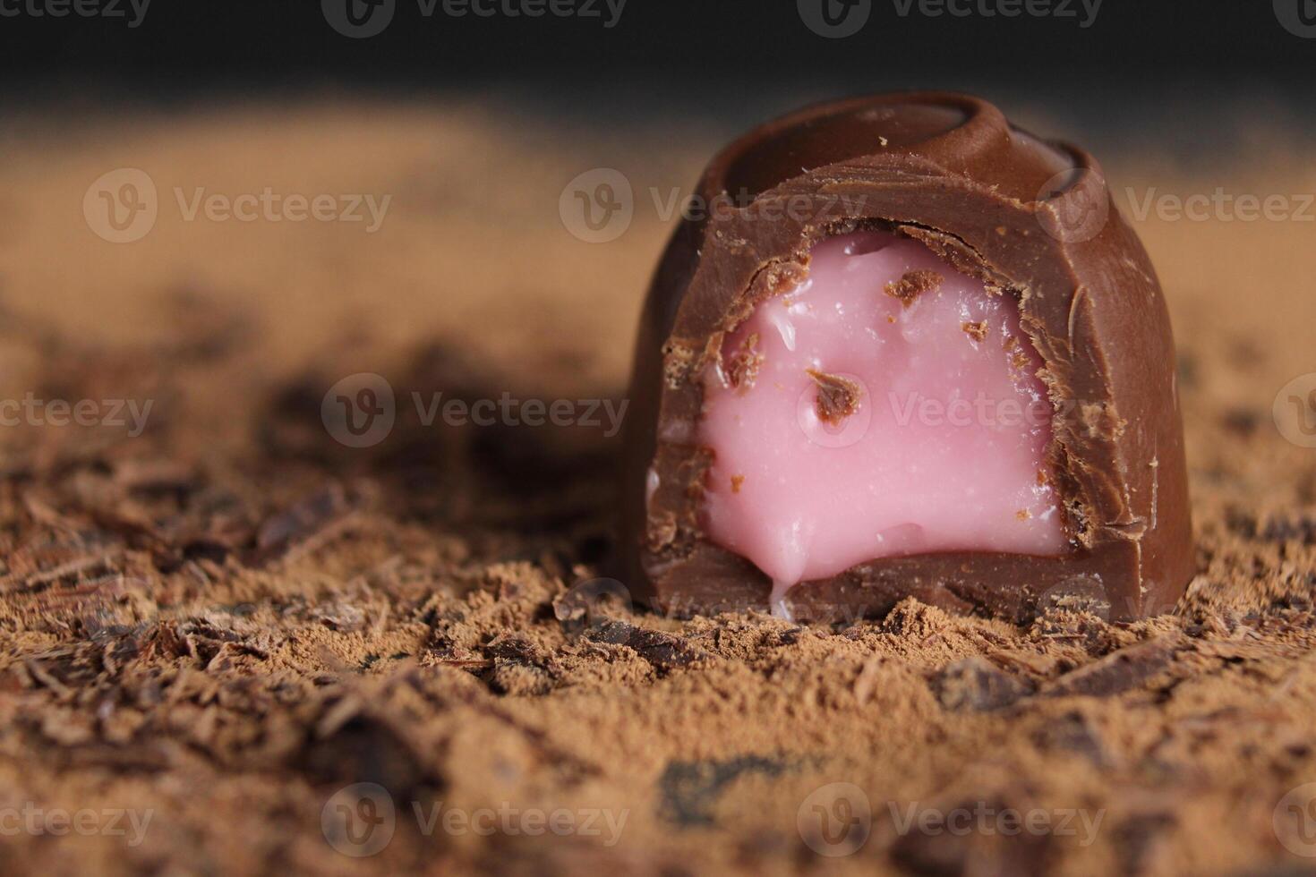 chocolate candy with stuffing rests on cocoa on a grey black background with a place to text a copy of the sweet chocolate brown background photo