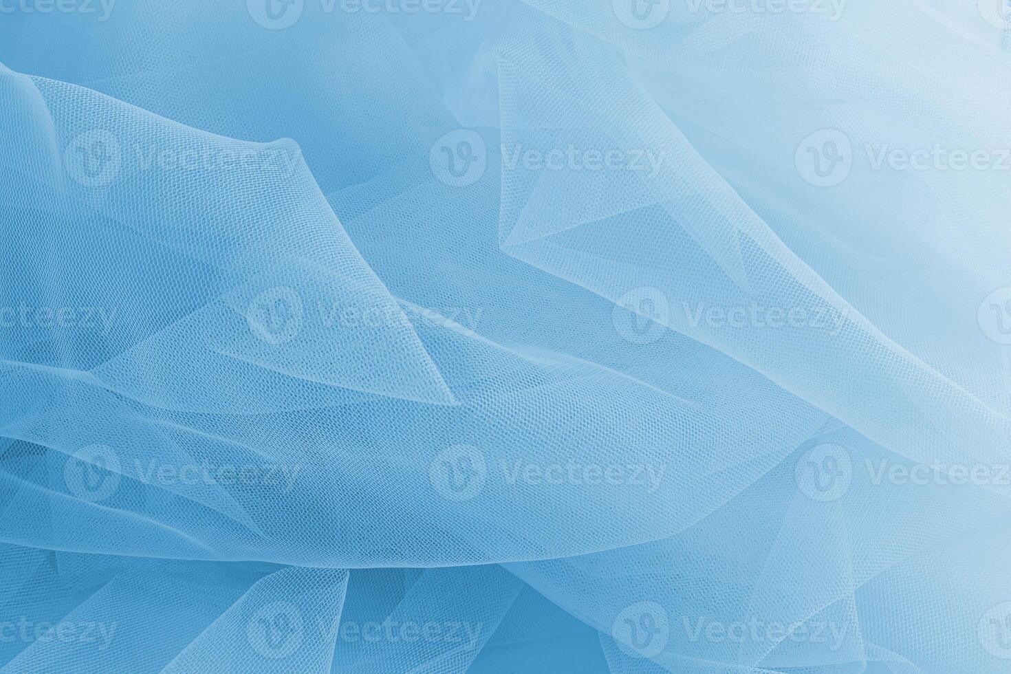 Abstract background of blue airy fabric. light folds of the transparent mesh of the veil of heavenly color. It is relevant for the layout of festive. photo