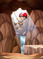 Boy abseiling into cave vector