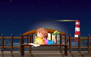 Little girl reading on the bench at night